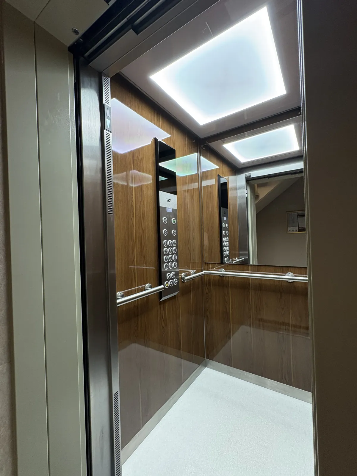Cabine d'ascenseur rénovée par Kréasteel : habillage bois, éclairage LED et sol clair